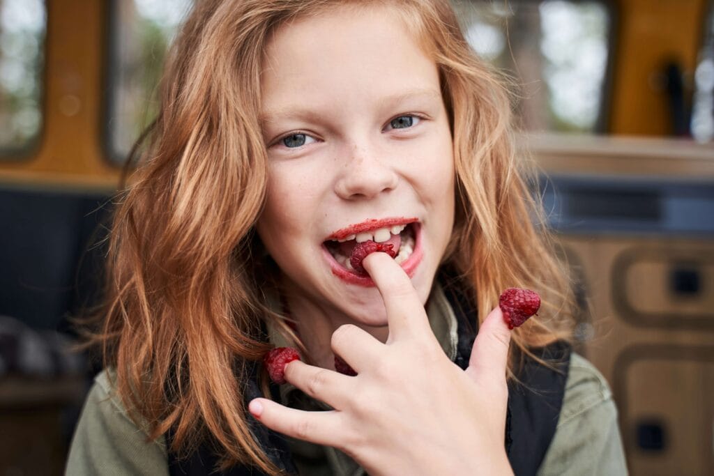 Ein Kind isst Himbeeren