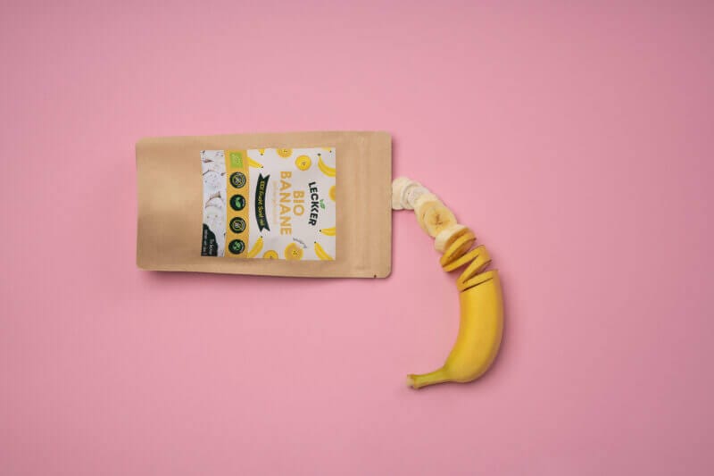 gefriergetrocknete Banane und frische Banane vor rosa Hintergrund