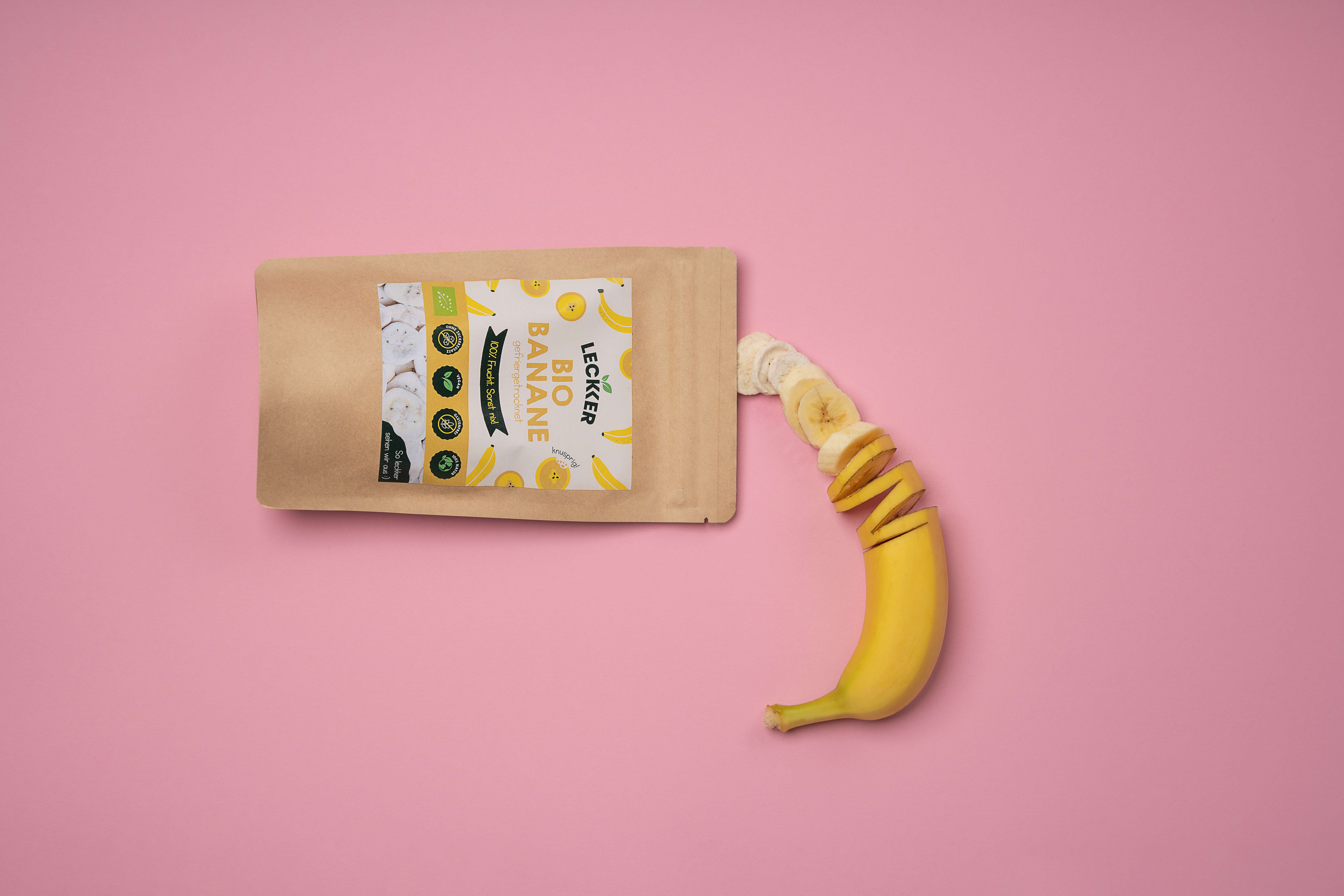 gefriergetrocknete Banane und frische Banane vor rosa Hintergrund