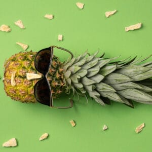 Ananas mit Sonnenbrille auf grünem Untergrund