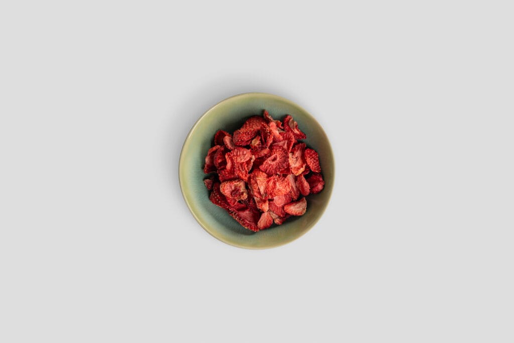 Kind sitzt in der Küche mit gefriergetrockneten Himbeeren