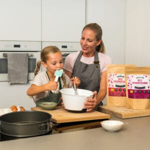 Mutter und Kind backen mit gefriergetrockneten Erdbeeren und Himbeeren
