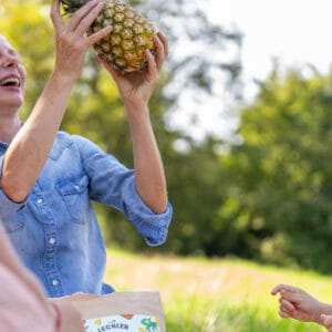 Frau hält Ananas in die Luft