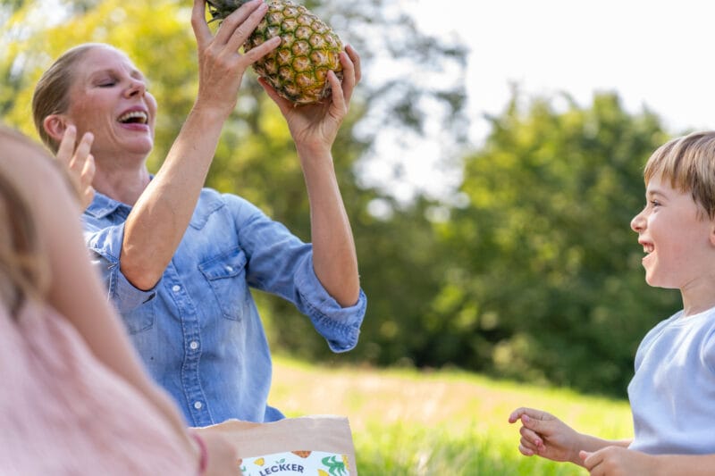Frau hält Ananas in die Luft