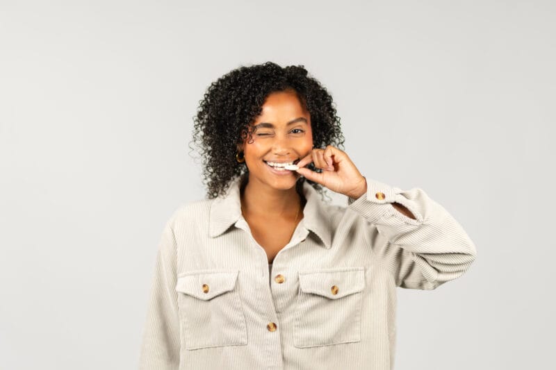 Frau vor einer weißen Wand mit gefriergetrockneten Früchten