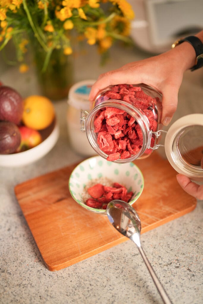 Kind sitzt in der Küche mit gefriergetrockneten Himbeeren