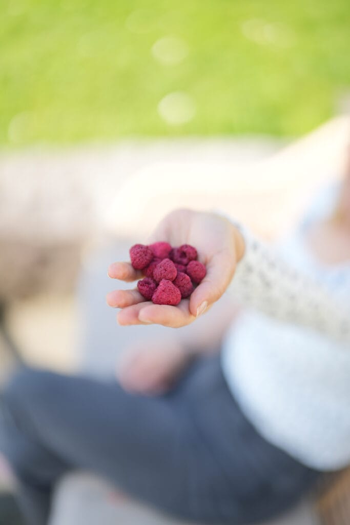 Kind sitzt in der Küche mit gefriergetrockneten Himbeeren